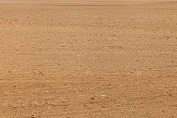 A vast brown ploughed cultivated soil, land texture background 