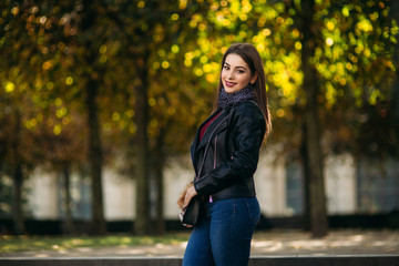 Stylish beautiful lady in a black leather jacket with a black bag. Attractive young woman smile