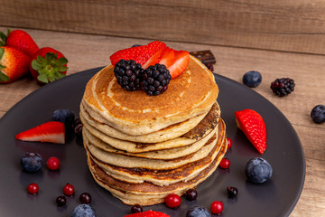 A stack of home-made pancakes with strawberries and blueberries