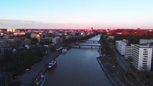 Aerial, drone shot over the Aurajoki river, overlooking the city of Turku, during sunset, in Varsinais-suomi, Finland