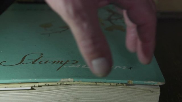 Closing an antique stamp album book in a grungy room.