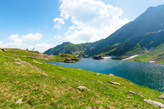 beautiful nature of romania mountains. lake balea in the valley. hills covered in grass, rocks and snow. wonderful summer sunny day with gorgeous cloudscape
