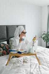Portrait of beautiful young woman in sunglasses and towel around her head. The girl works at home. Freelancer portrait. Freelance girl working at home, work online, home office.