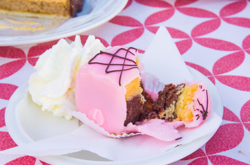 vanilla and chocolate cupcakes covered with strawberry icing and whipped cream