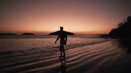 A man enjoying a walk on the beach of Costa Rica during sunset - wide shot