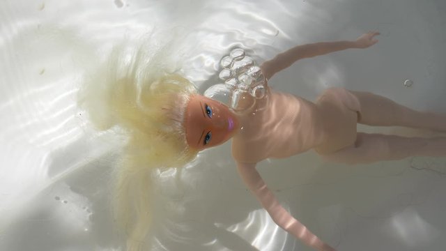 Scary psycho Caucasian doll inside bathtub drowning and filling up with water