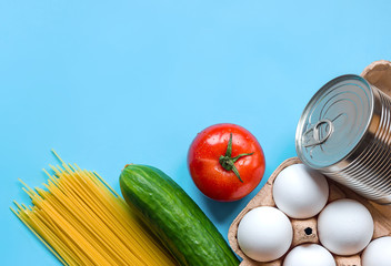  Food supplies in times of crisis with isolation against a blue background, food delivery donation, cucumber tomato paste dried mushrooms eggs toilet paper coronovirus quarantine, copy space for text