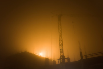 Tower crane at construction site in the misty morning sunlight