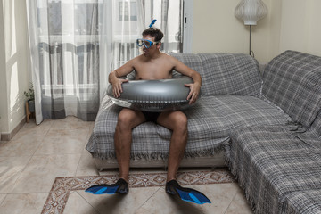 Male swimmer sitting on sofa at home