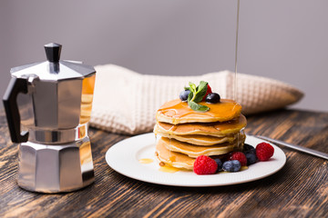 Woman pouring maple syrup on tasty pancakes.
