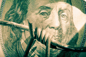 Economic warfare, sanctions and embargo busting concept. Close up barbed wire against US Dollar...