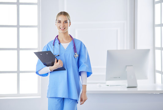 Smiling female doctor with a folder in uniform standing