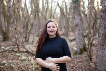 Pregnant beautiful happy woman walks in the autumn forest, she breathes the clean forest air, which is good for her health