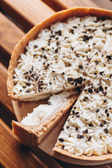 banana-caramel pie on the basis of a small cake with top cream and grated chocolate on a wooden...