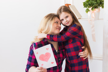 Happy mother's day. Child daughter congratulates mom and gives her postcard. Mum and kid girl smiling and hugging. Family holiday and motherhood.