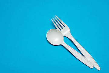 disposable spoon and fork made of corn starch on a blue background. biodegradable eco friendly...