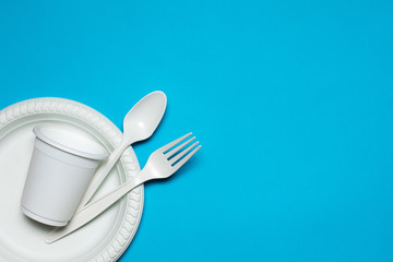 disposable spoon, fork, glass and plate of corn starch on a blue background. biodegradable...