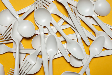 disposable spoons and forks of corn starch lie on a yellow background. biodegradable environmentally friendly disposable tableware. isolate. replacement of plastic with modern biomaterials. close-up