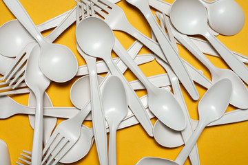 disposable spoons and forks of corn starch lie on a yellow background. biodegradable...