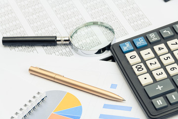 Business financial documents, office calculator and pen on the table. Numbers and graphs