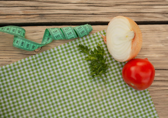 onion, tomato, parsley and measuring tape lie on a tissue napkin on a table in the garden, top...