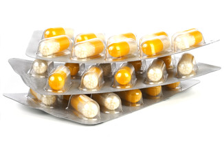 A close up of a pack of yellow and white pills on white background. Detailed view of medication packaging