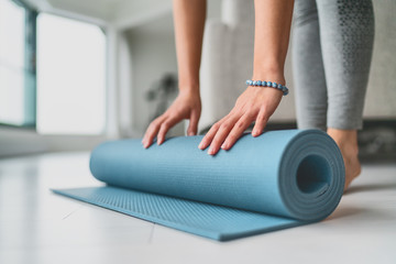 Yoga at home woman rolling exercise mat in living room of house or apartment condo for morning...