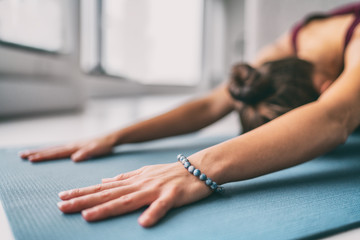 Yoga meditation wellness background - woman doing childs pose stretch on exercise mat - training...