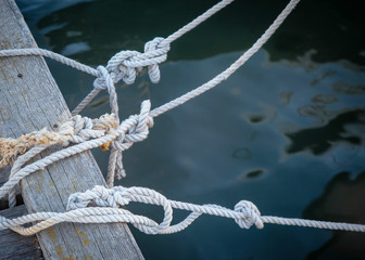 Fototapeta premium knots on sea ropes are tied to a wooden Board or pier. The concept of safety on the water.