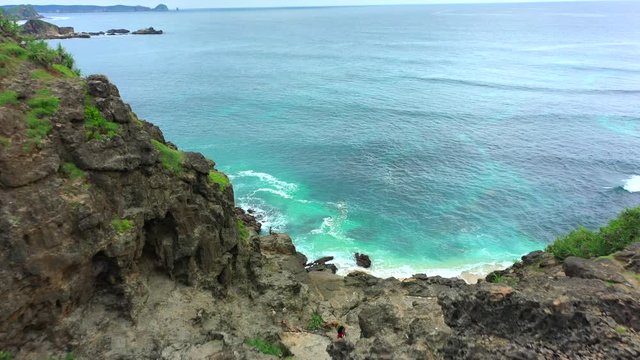 Rocky shore of the sea with waves on the background. Sunny day in Lombok, Indonesia.