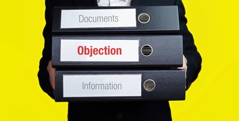 Objection – finance/economics. Man carries a stack of 3 file folders. A folder has the label Objection. Business, statistics concept - obrazy, fototapety, plakaty