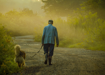 Mężczyzna w kaloszach na spacerze z psem o poranku
