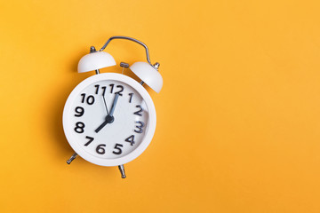 White vintage alarm clock on yellow color background