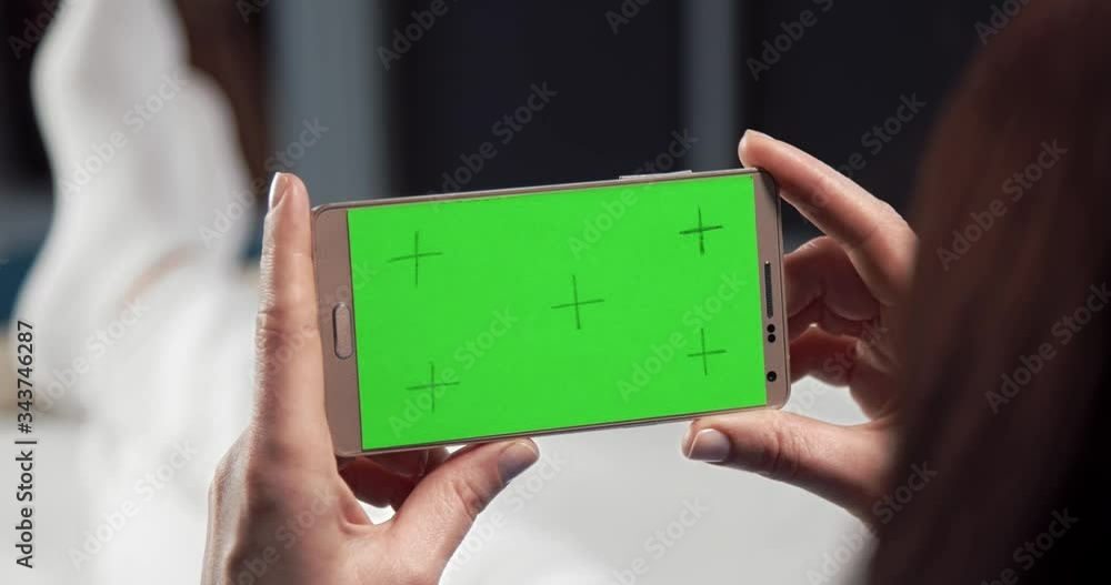 Poster close up of smartphone with green empty screen that holding woman in hands while sitting on couch. y