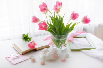Obraz na płótnie Canvas postcard good morning. Still life : a Cup of tea, a bouquet of pink tulips, marshmallows on a light background near the window.