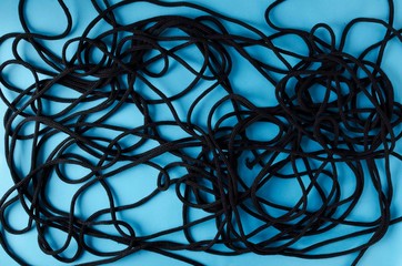 Top view of entangled black rope on the blue background