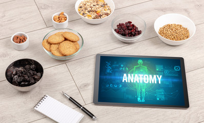 ANATOMY concept in tablet with fruits, top view