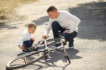 Family in a park. Father with son. People repare the bike.