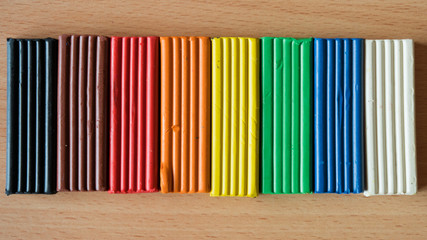 Multi-colored pieces of children's plasticine on a wooden table.