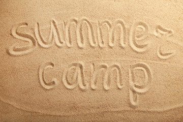 Inscription summer camp on beach sand. Top view