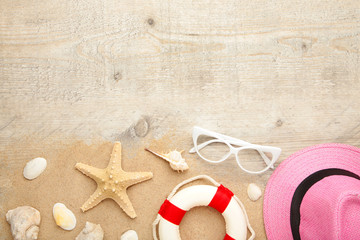 Beach hat with seashells and sand on light background