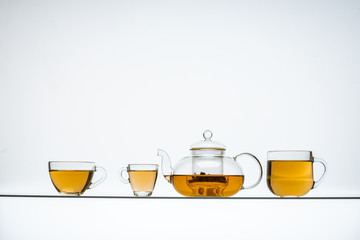 glass teapot and cups with hot tea on table, close view    