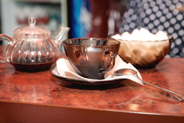 Glass teapot with brewed black tea and a glass cup close-up on the table
