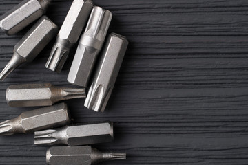 Replaceable nozzles for a screwdriver. Set of bits for a screwdriver on a black wooden background.