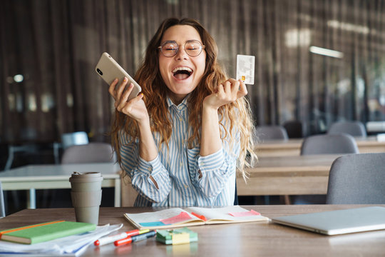 Image of excited charming woman showing credit card and mobile phone