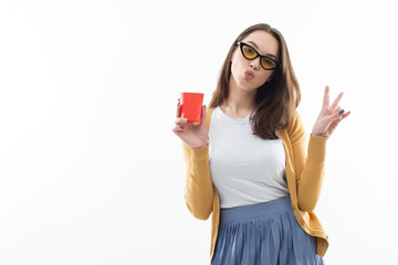 Brunette in a yellow sweater drinks coffee from a red cup
