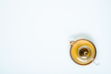 glass teapot and cups with hot tea on table, top view