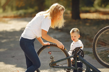 Obraz premium Family in a park. Mother with son. People repare the bike.