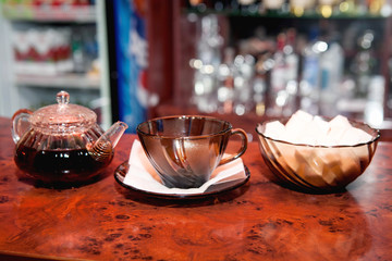 Glass teapot with brewed black tea and a glass cup close-up on the table