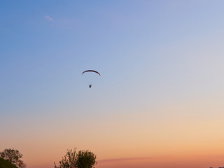 Paraglider flies on a paraglider over the city on a warm summer evening
